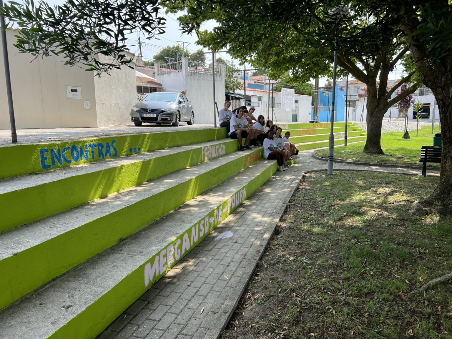 Escadas pintadas em verde e grupo de jovens voluntários sentados.