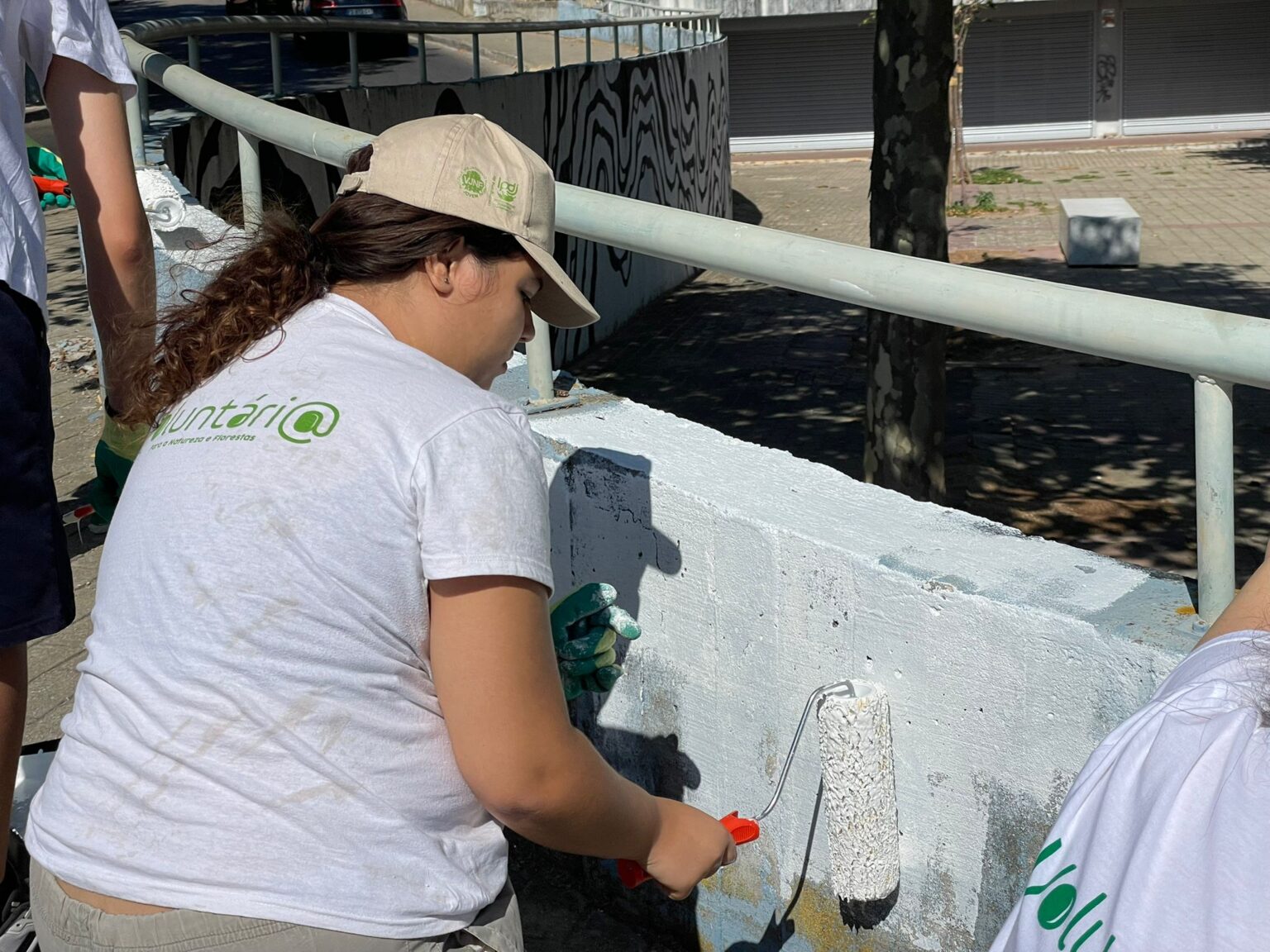Voluntária pinta muro de branco na Freguesia de São Sebastião.